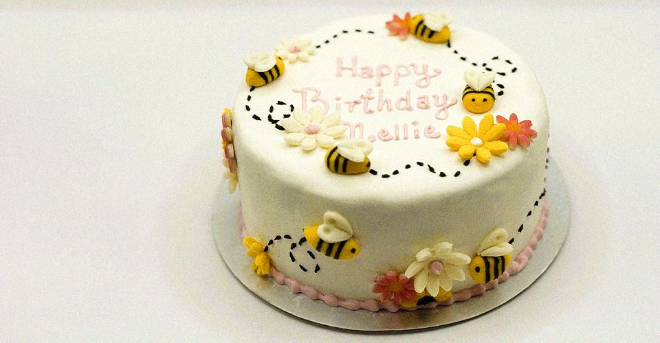 decorated cake featuring bees and colorful flowers