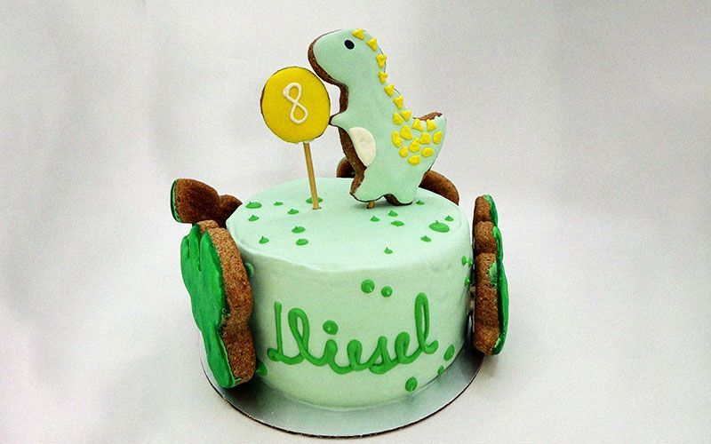 colorful cake topped with a playful dinosaur for a pet themed party